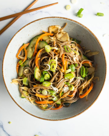 cold soba noodle salad with ginger-soy-dressing in a bowl on a table with chopsticks