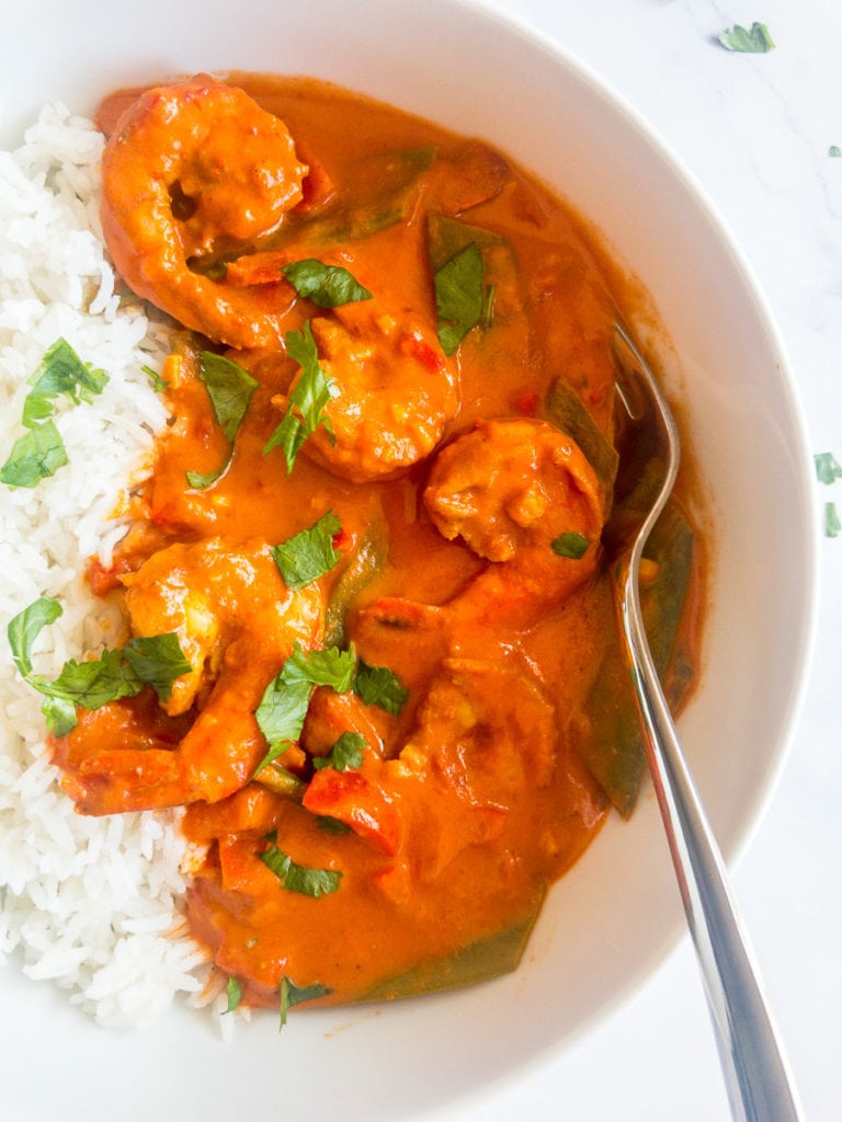 indian shrimp curry with rice in a white bowl with a fork