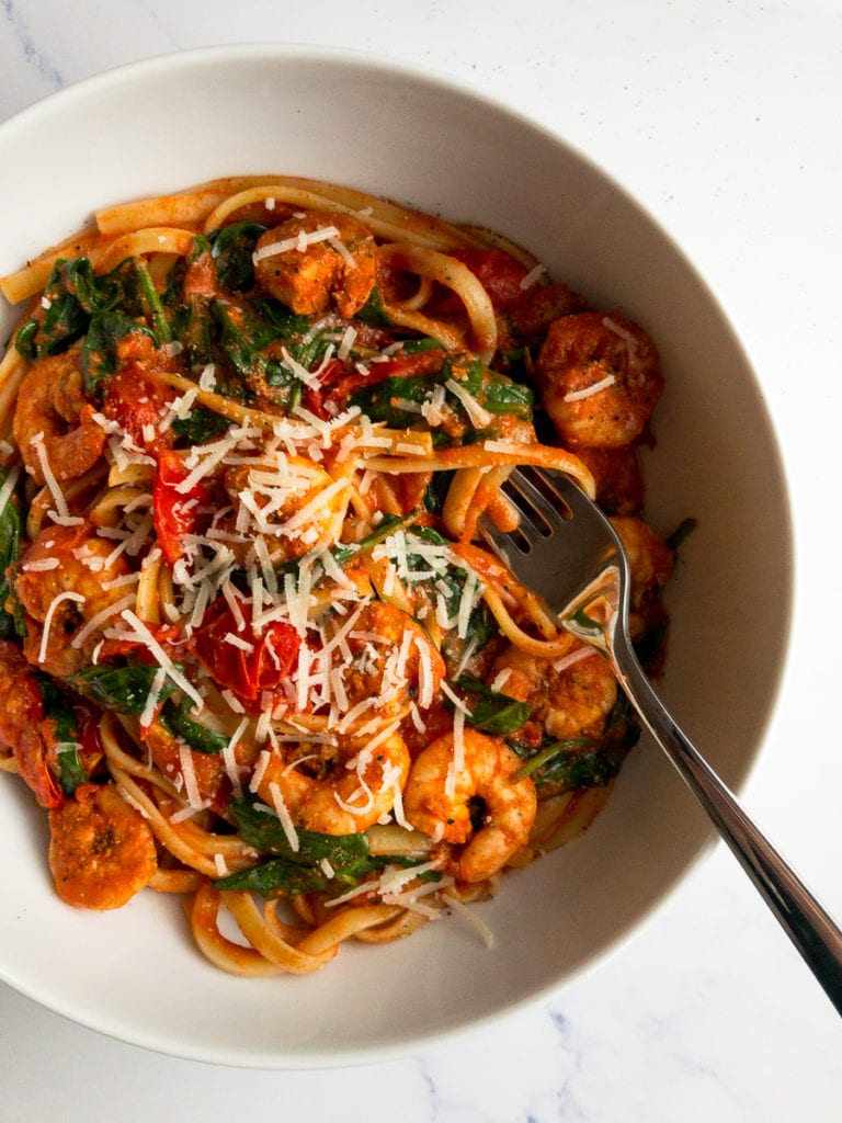 spicy cajun shrimp pasta in a white bowl with a fork