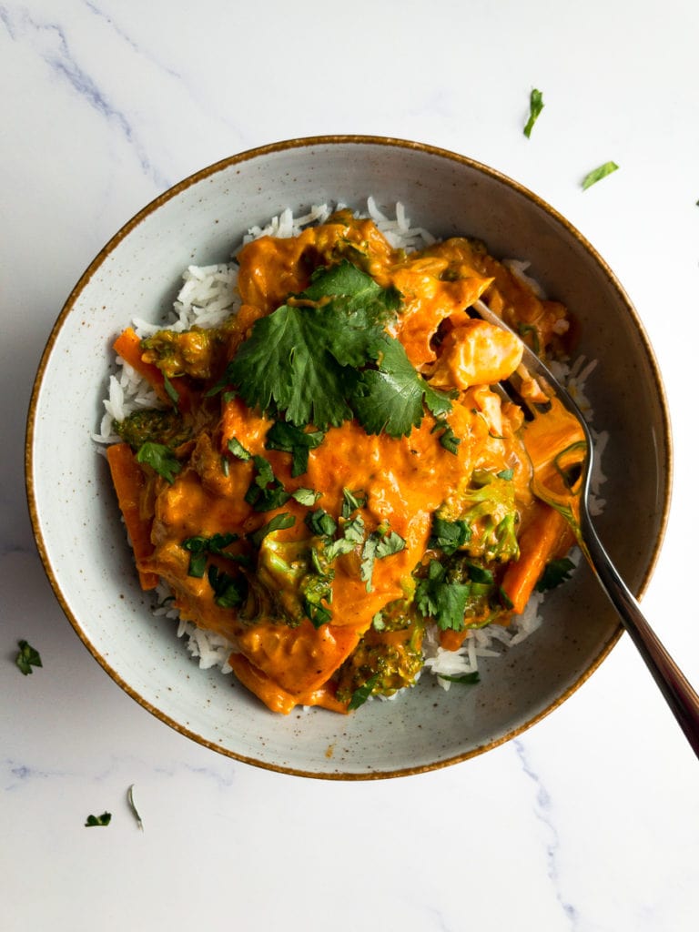 salmon coconut curry on rice and a fork in a bowl