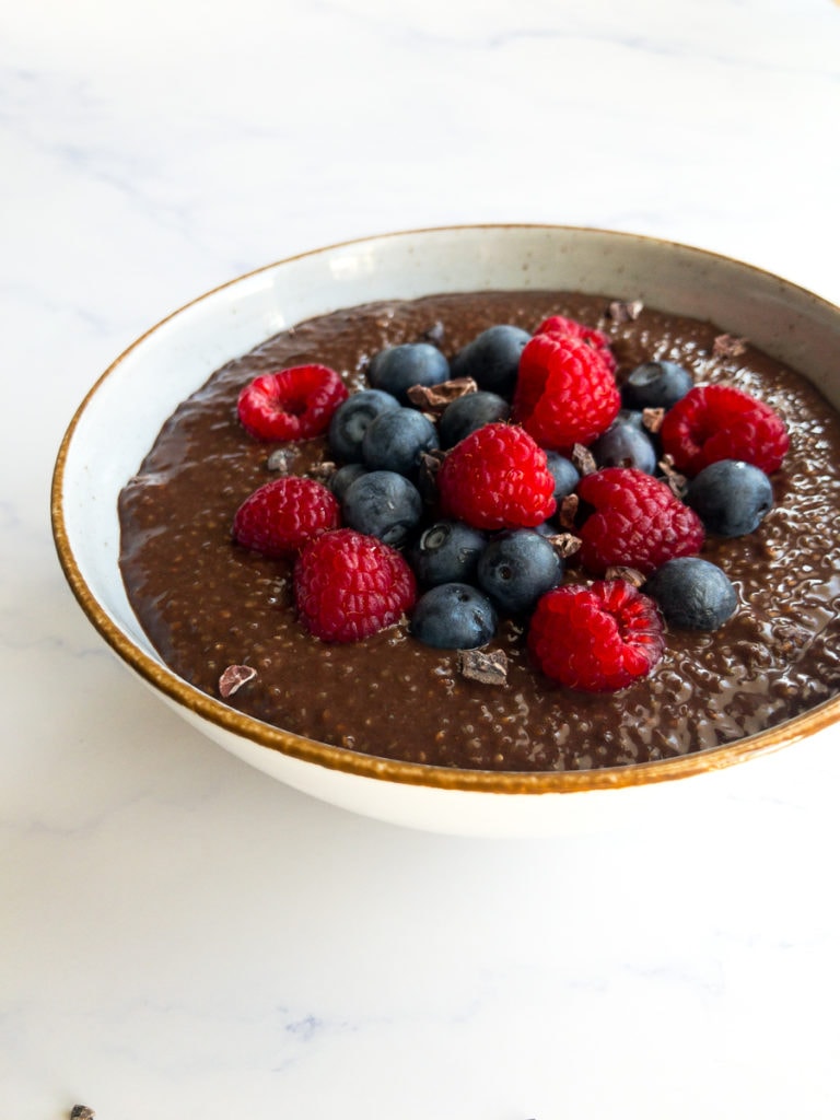 chocolate chia seed pudding topped with blueberries and raspberries in a bowl