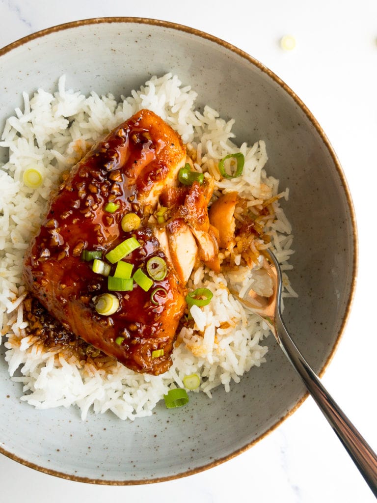 honey sriracha salmon over rice in a bowl with a fork