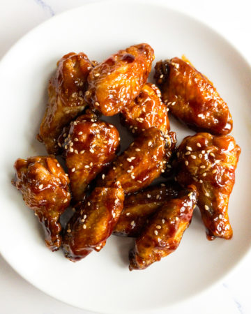 teriyaki chicken wings garnished with sesame seeds on a white plate