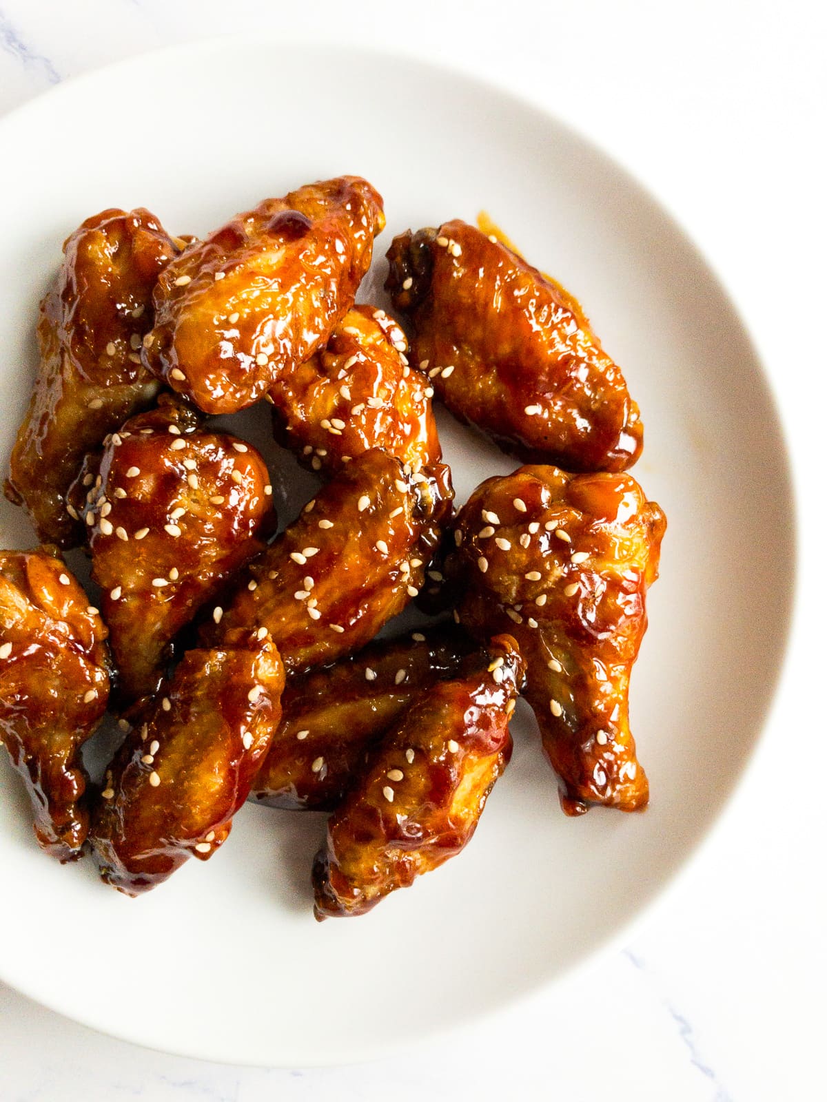 teriyaki chicken wings garnished with sesame seeds on a white plate