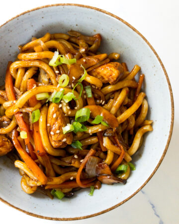 chicken yaki udon garnished with green onion and sesame seeds in a bowl