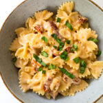 creamy sun-dried tomato pasta garnished with fresh basil leaves in a bowl
