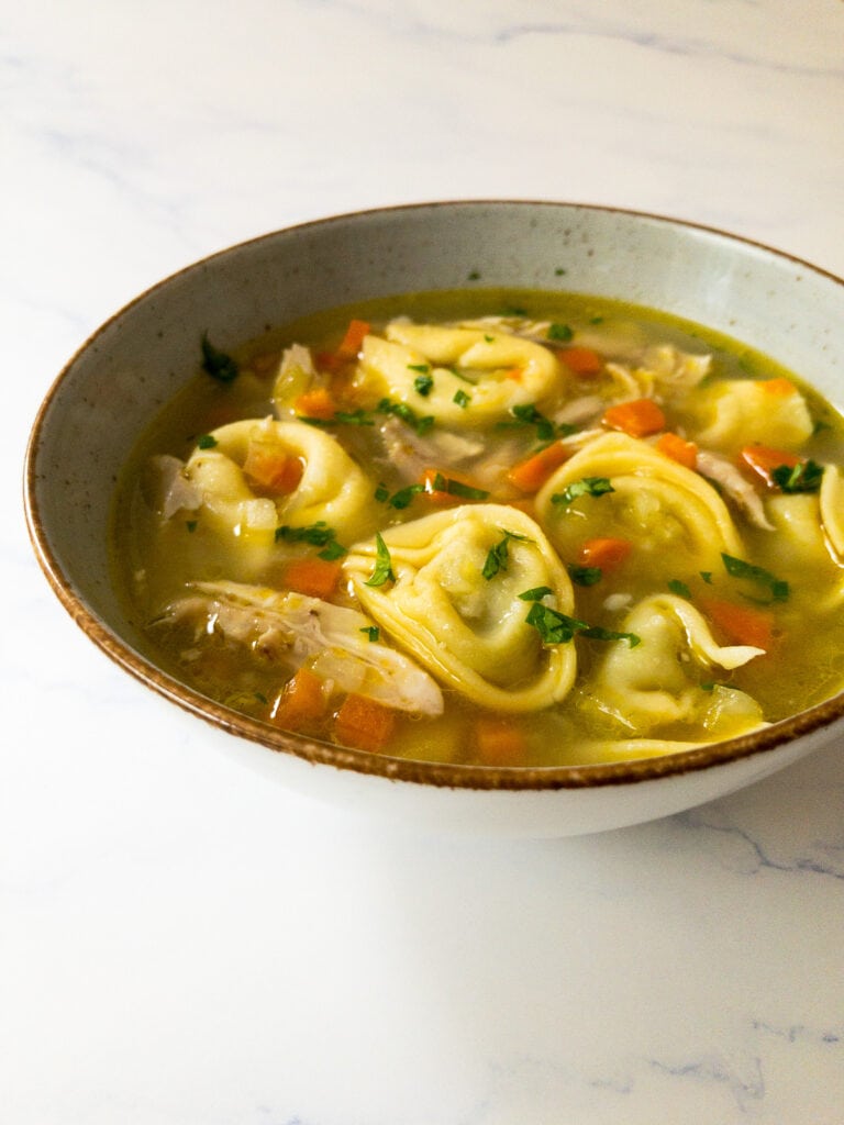 chicken tortellini soup garnished with parsley in a bowl
