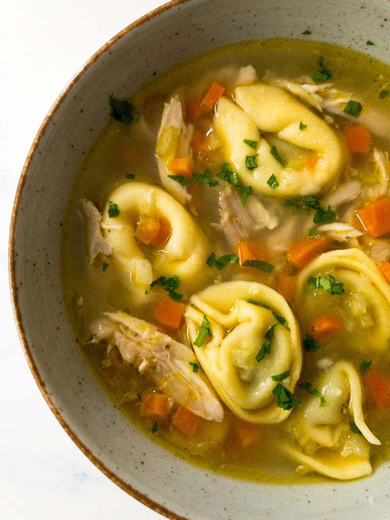 chicken tortellini soup garnished with parsley in a bowl
