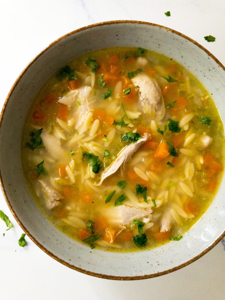 lemon chicken orzo soup garnished with parsley in a bowl