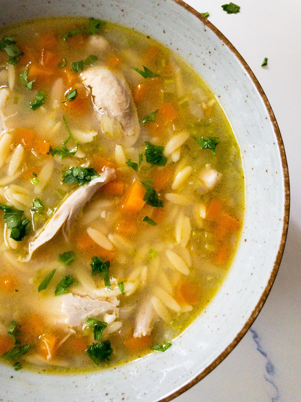 lemon chicken orzo soup garnished with parsley in a bowl
