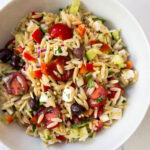 greek orzo salad in a white bowl
