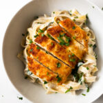 lemon chicken pasta garnished with parsley in a white bowl