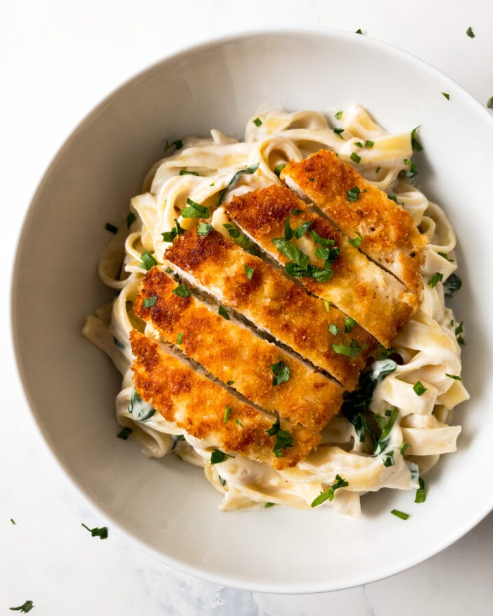 lemon chicken pasta garnished with parsley in a white bowl