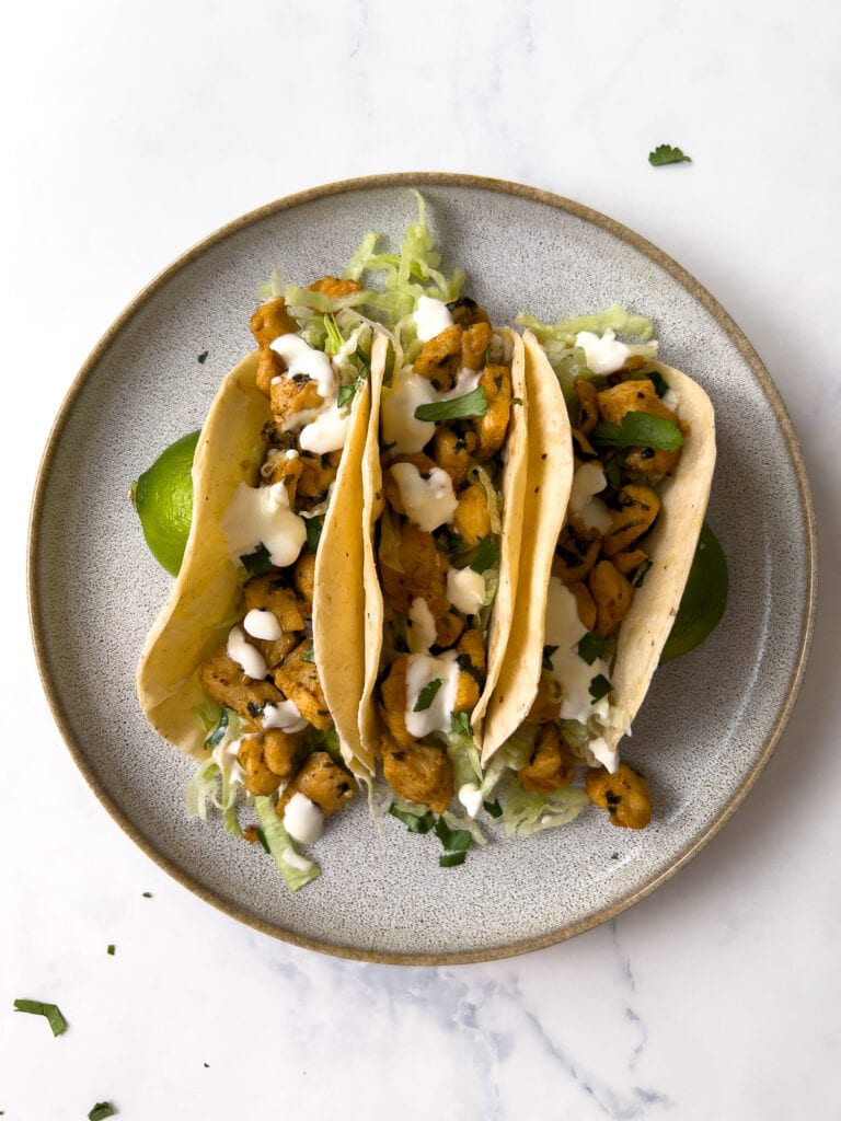 cilantro lime chicken tacos with lettuce, guacamole, and sour cream on a plate