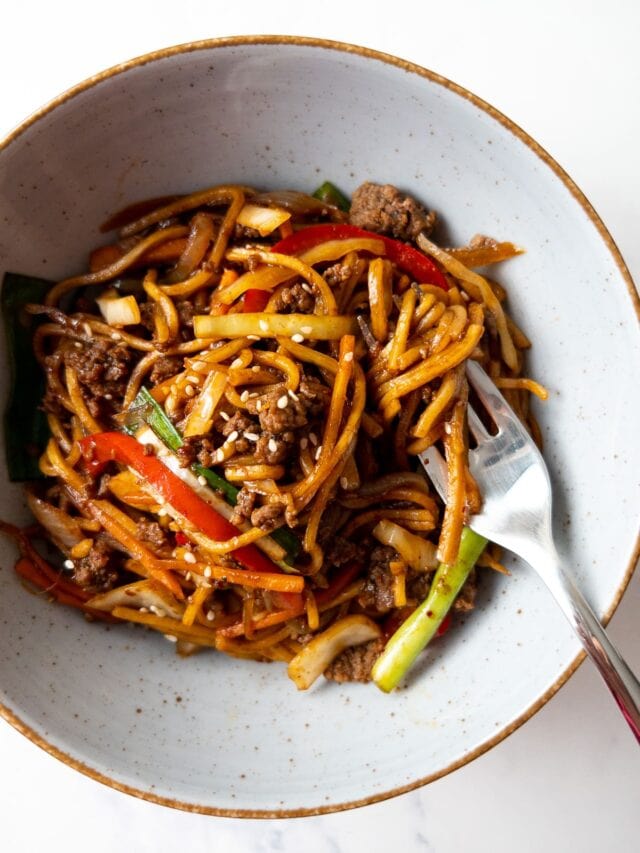 ground beef stir fry noodles garnished with sesame seeds in a bowl