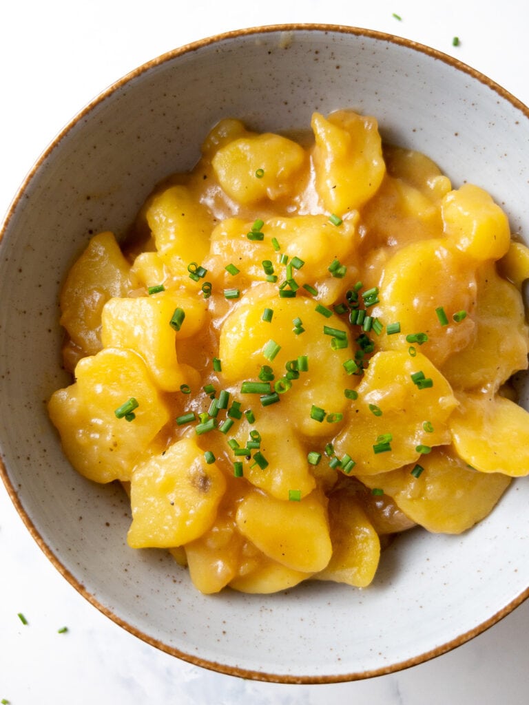 german potato salad garnished with chives in a bowl