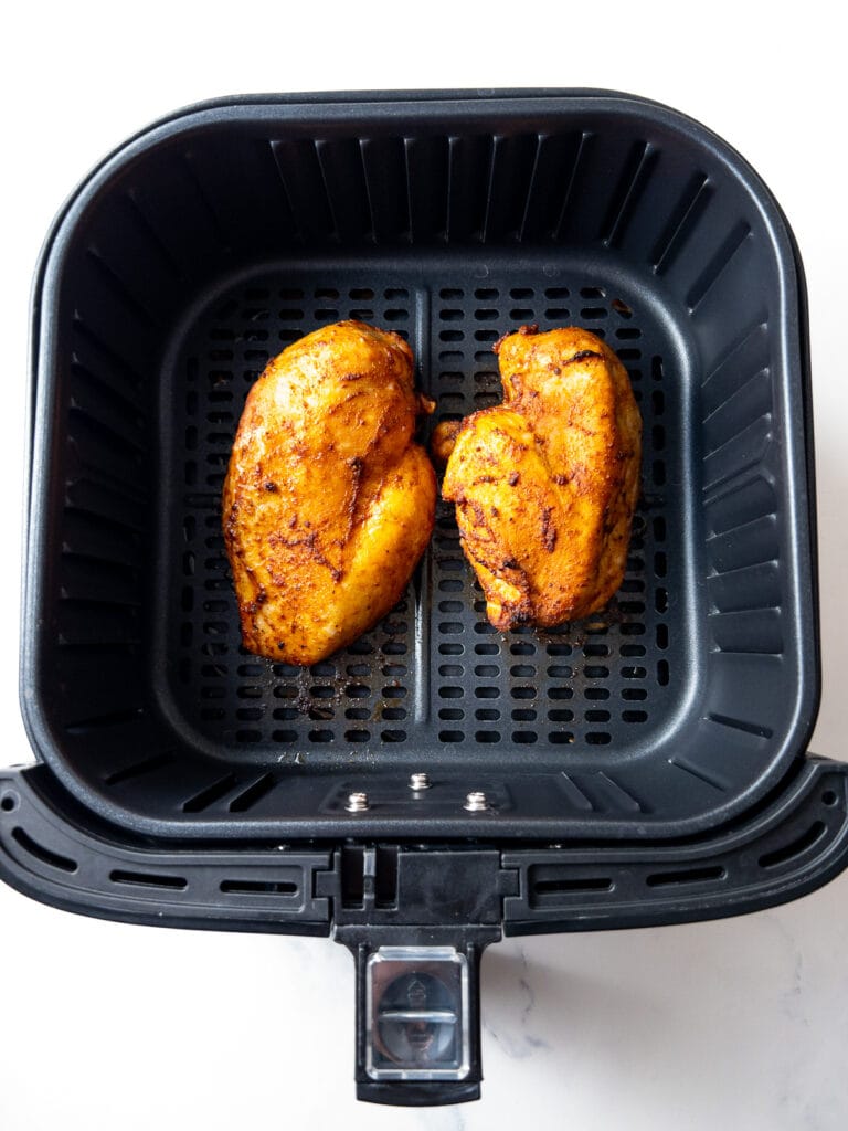 two air fryer chicken breasts after cooking in the air fryer basket