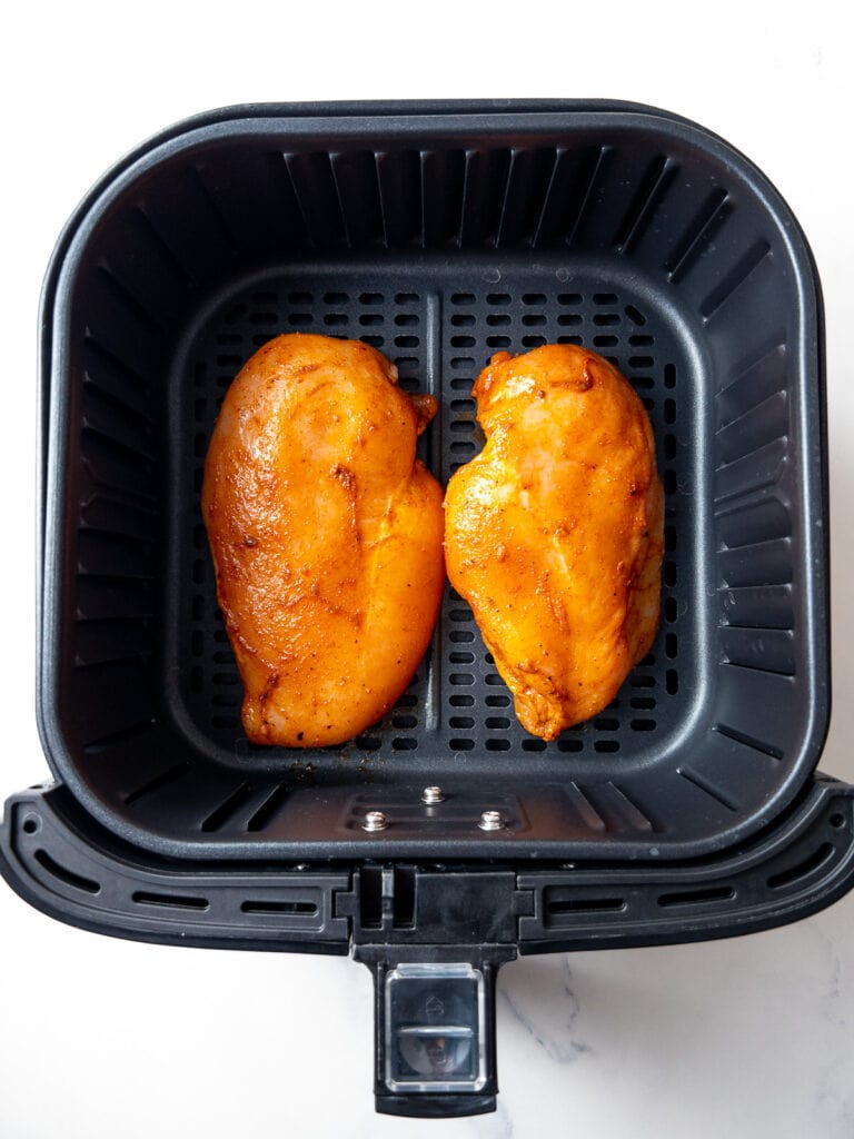 two air fryer chicken breasts before cooking in the air fryer basket