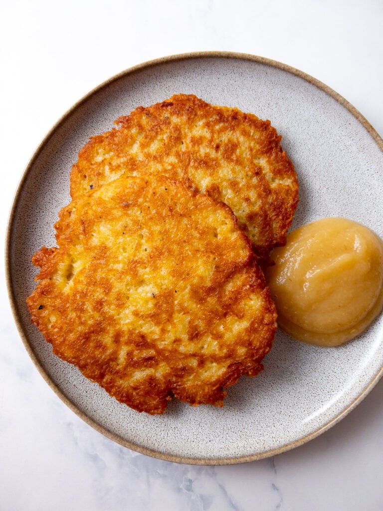 two german potato pancakes on a plate with some applesauce