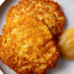 two german potato pancakes (kartoffelpuffer) on a plate with some applesauce