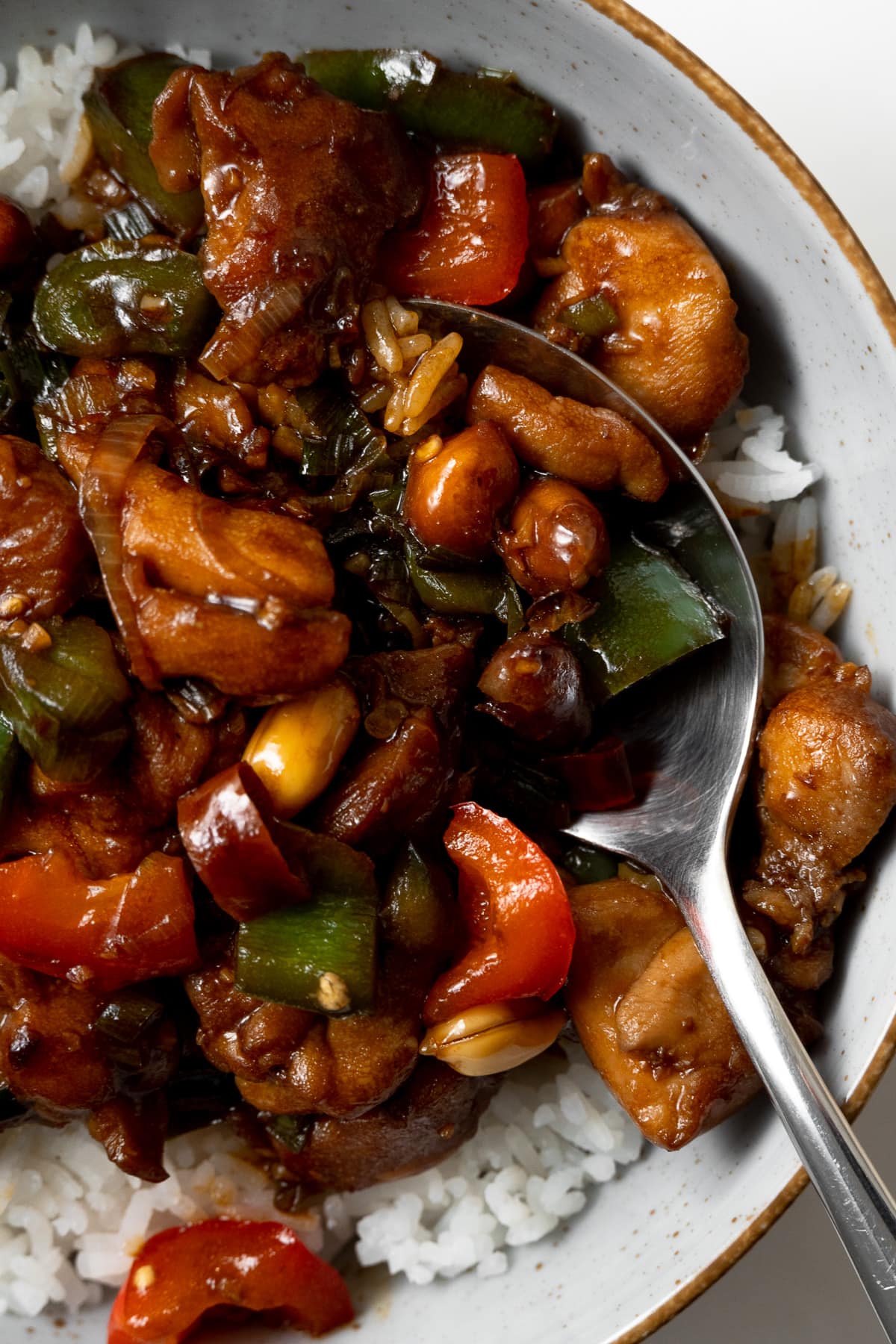kung pao chicken served over rice in a bowl with a spoon