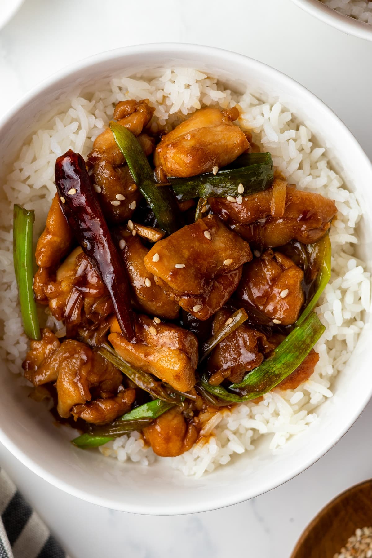 mongolian chicken served over rice in a white bowl