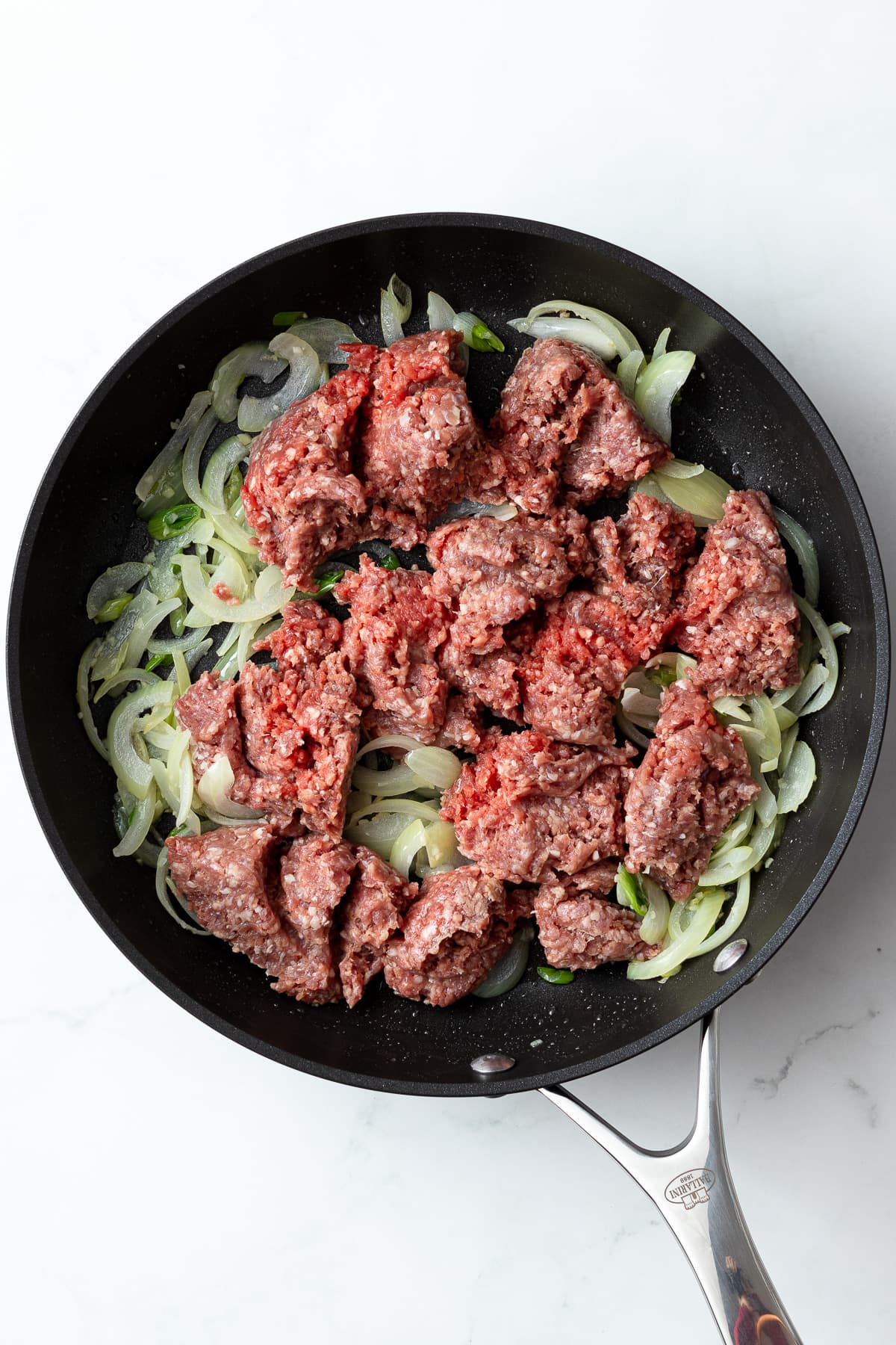 cooked onions and garlic with raw ground beef in a pan
