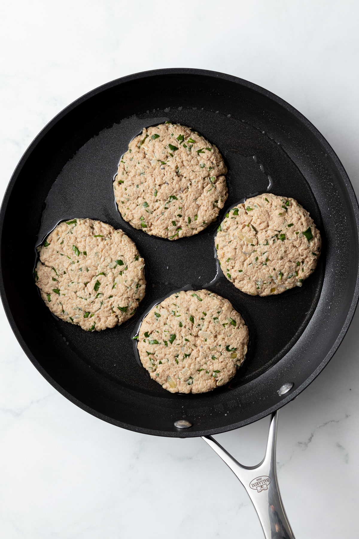 four tuna patties before being seared in a pan with some oil