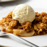 apple crisp with vanilla ice cream on a plate with a fork