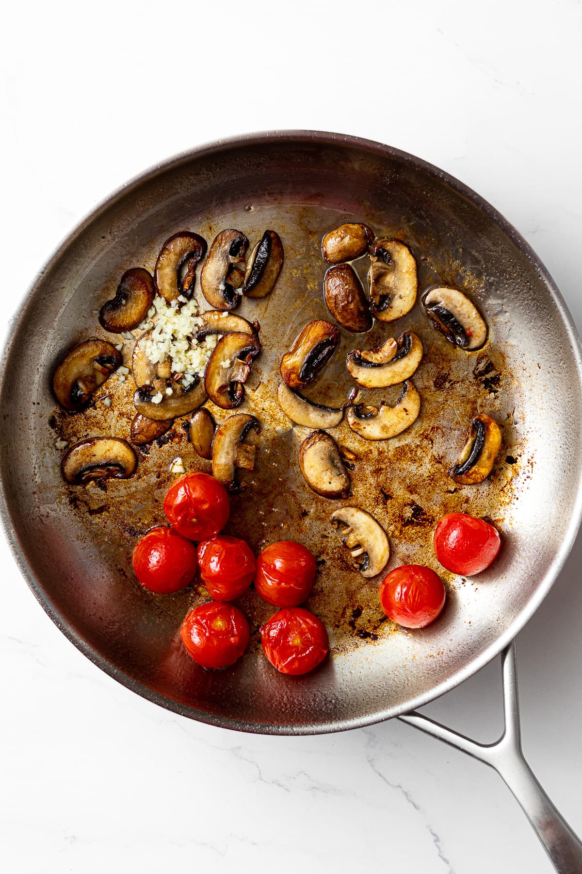 sautéed cherry tomatoes and mushrooms in a pan with fresh minced garlic added