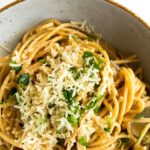 lemon garlic pasta in a bowl with a fork topped with grated parmesan and chopped parsley