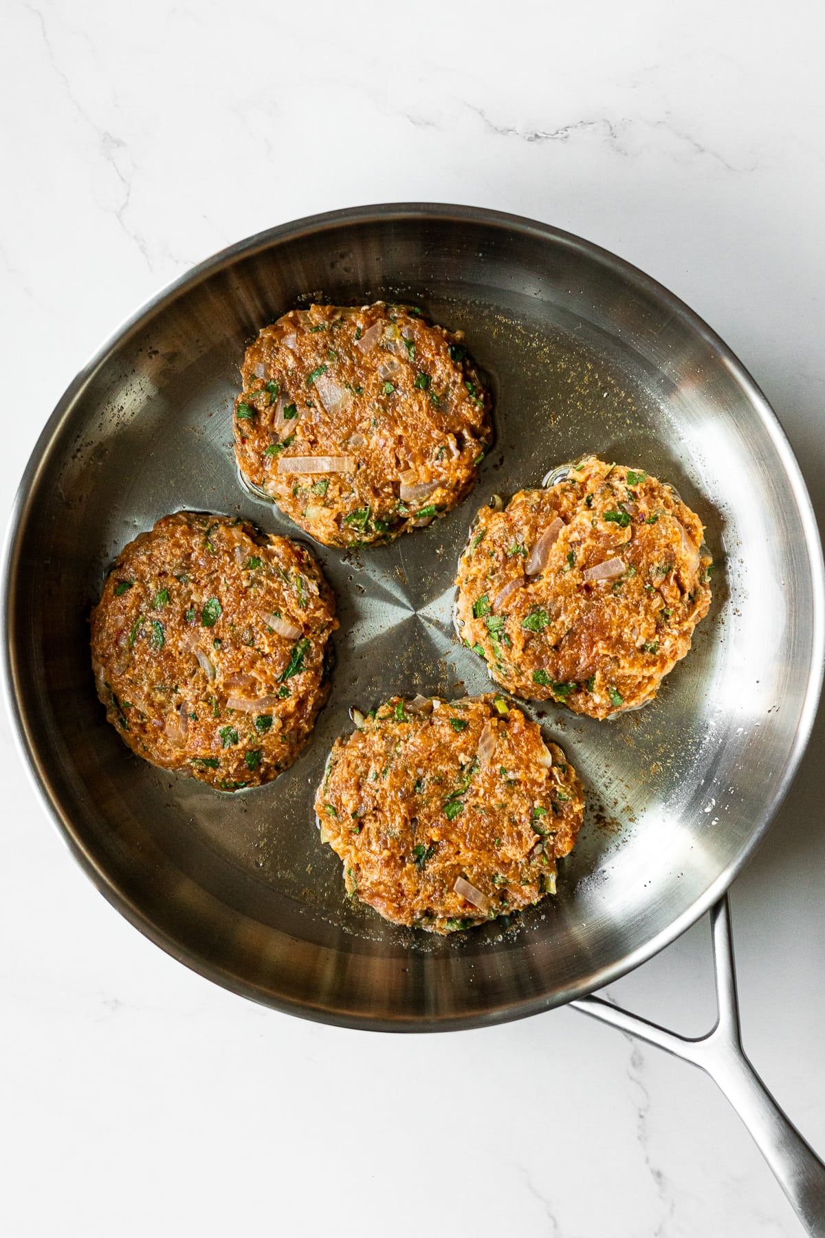 four raw chicken patties in a pan on a table