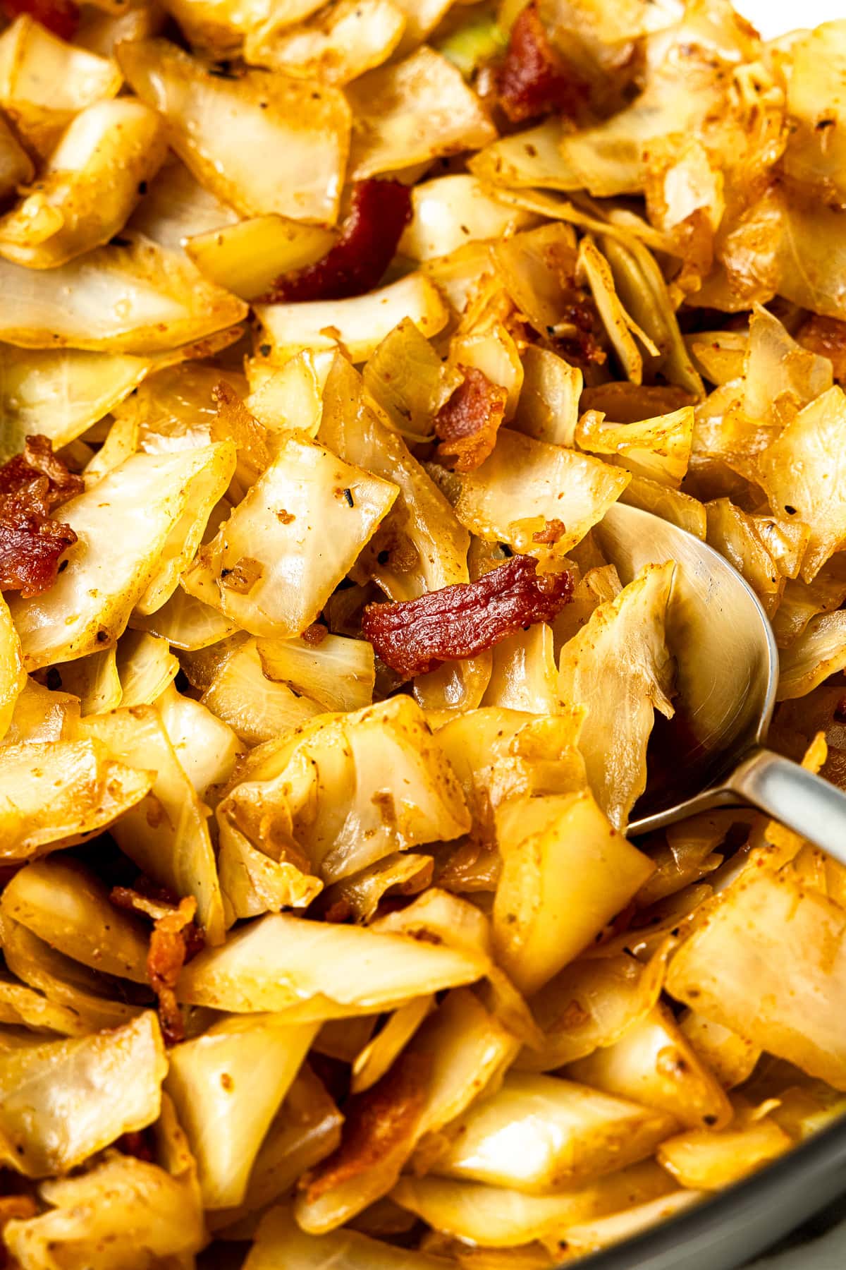 fried cabbage with bacon and onions and a spoon