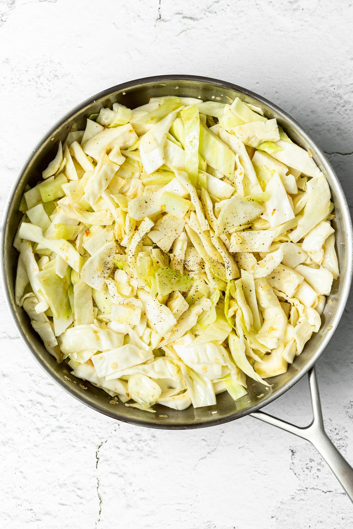 sautéed cabbage and aromatics in a pan with salt and pepper
