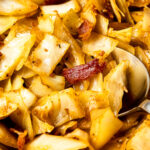 fried cabbage with bacon and onions and a spoon
