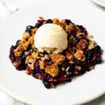frozen berry crisp with a scoop of vanilla ice cream on a plate