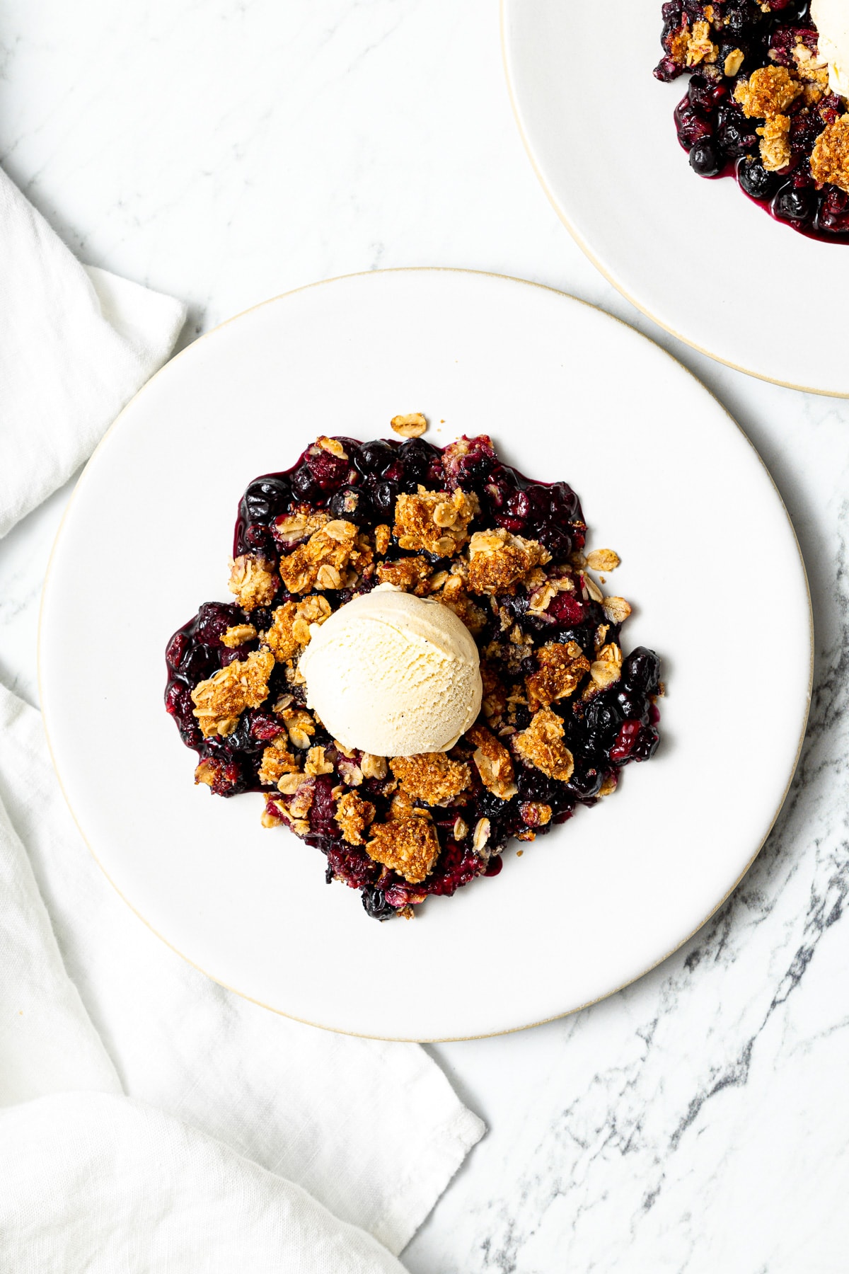 frozen berry crisp with a scoop of vanilla ice cream on a plate