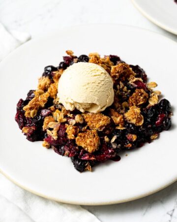 frozen berry crisp with a scoop of vanilla ice cream on a plate
