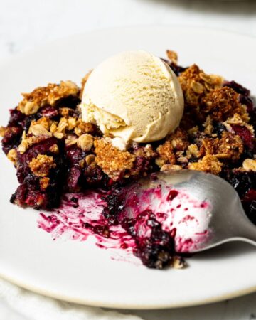 frozen berry crisp with a scoop of vanilla ice cream and a spoon on a plate