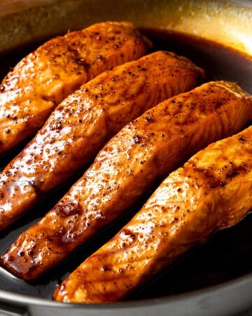 air fryer teriyaki salmon in a pan with some additional teriyaki sauce