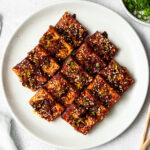 sliced korean braised tofu (dubu jorim) on a plate garnished with sesame seeds