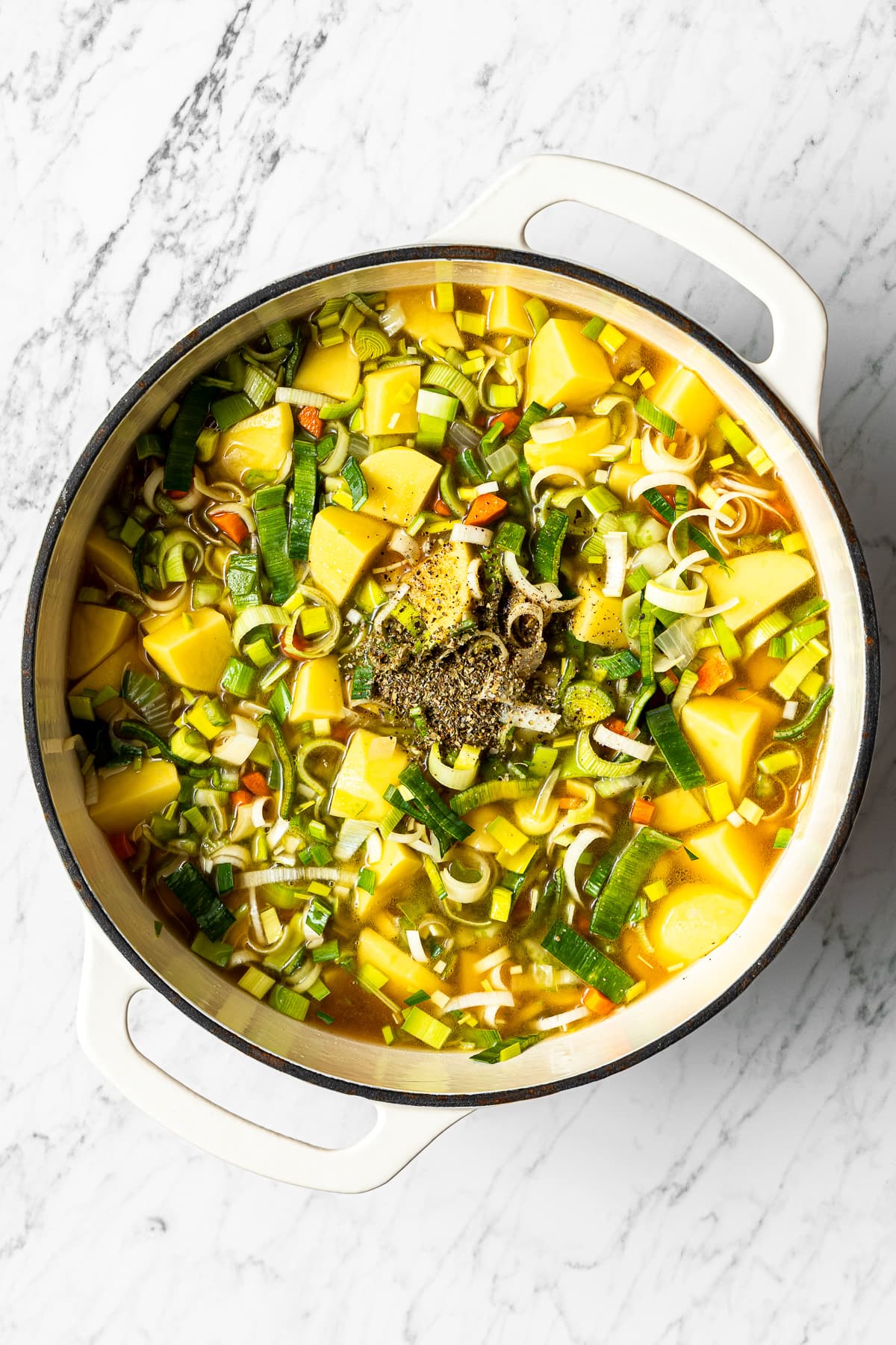 all vegetables and liquids for german potato soup in a pot with dried marjoram added