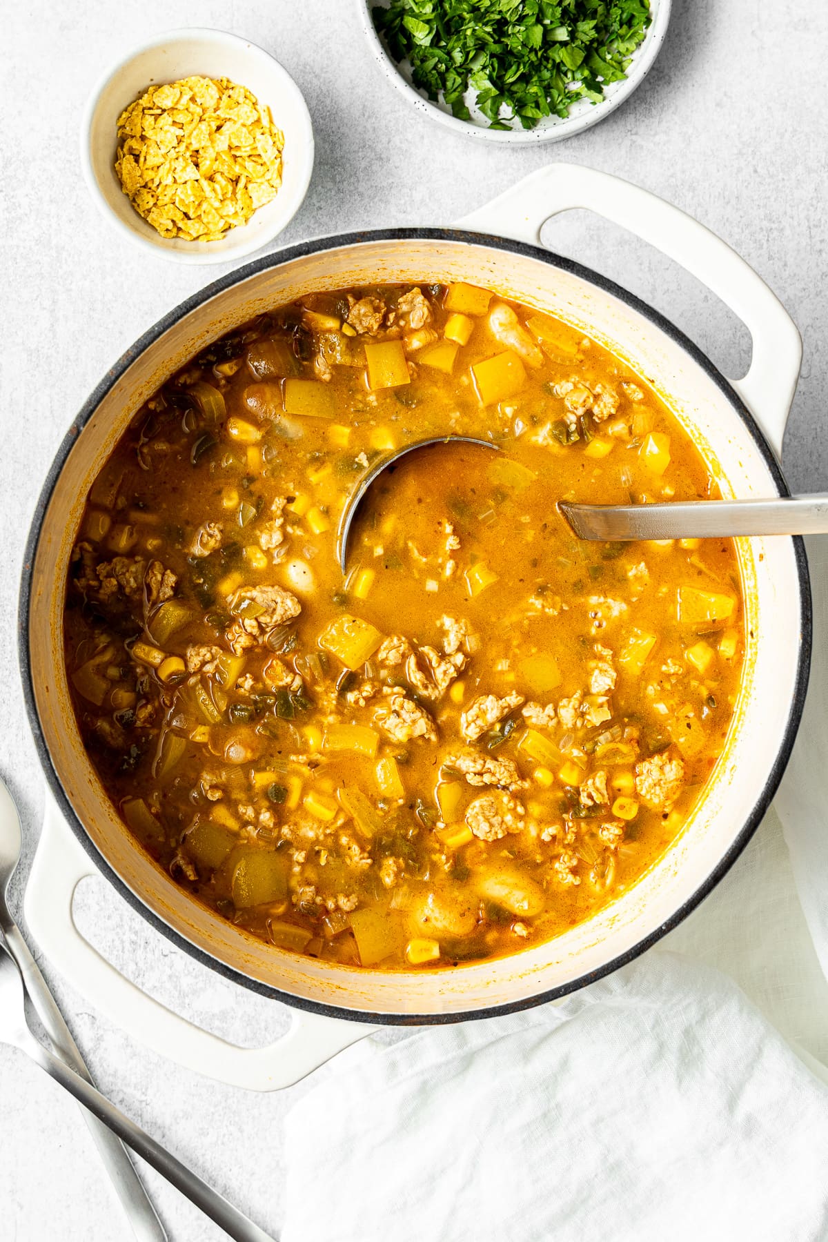 white ground chicken chili in a large pot with a soup ladle