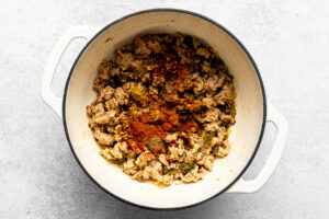 cooked aromatics and ground chicken in a pot with spices added