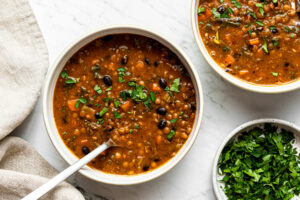 black bean and lentil soup garnished with chopped parsley in a bowl with a spoon