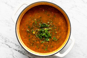 a large pot with black bean and lentil soup and some kale added to the pot