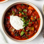 sweet potato black bean chili in a bowl garnished with chopped cilantro and sour cream