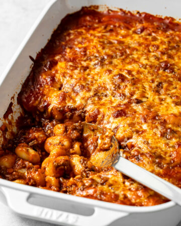 baked gnocchi bolognese in a baking dish with a large spoon