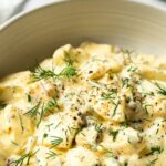 dill pickle egg salad garnished with chopped dill and black pepper in a bowl