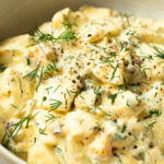dill pickle egg salad garnished with chopped dill and black pepper in a bowl